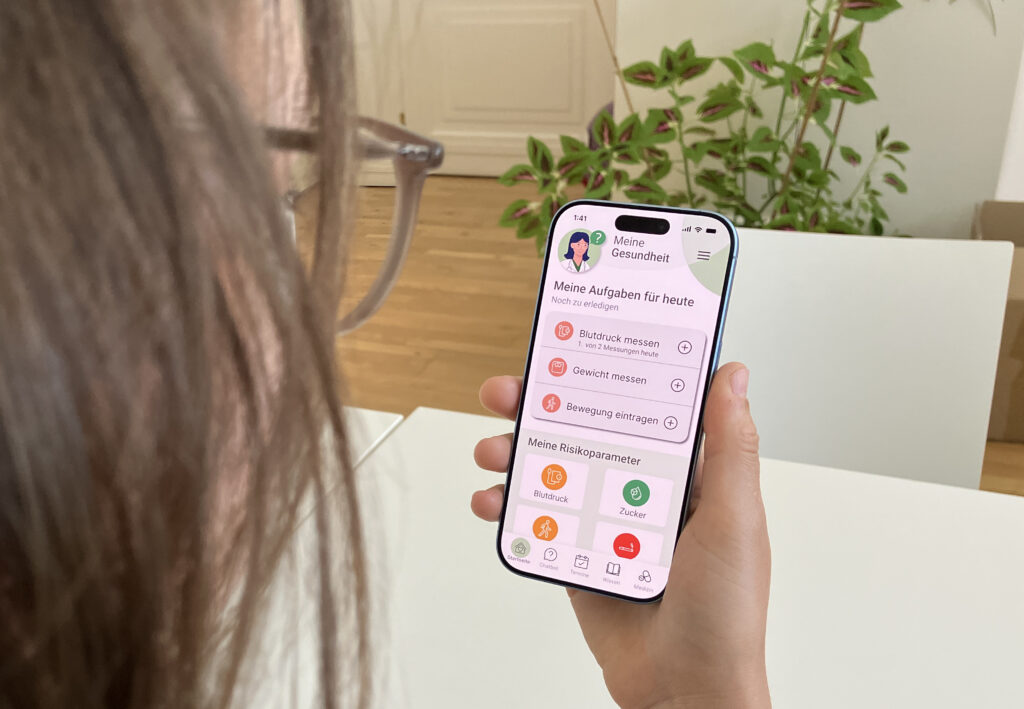 Eine Frau hält ein Handy in der Hand, am Display ist die Ansicht einer Gesundheitsapp zu sehen.