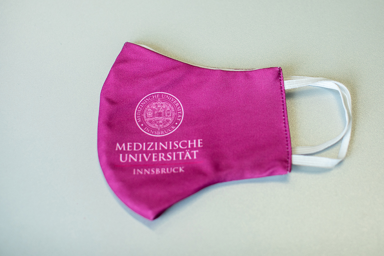 Mund-Nasen-Schutz mit Logo der Medizinischen Universität Innsbruck magenta
